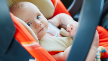 baby girl in orange infant car seat