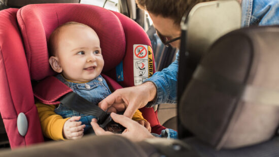 Mom buckling a baby into a car seat