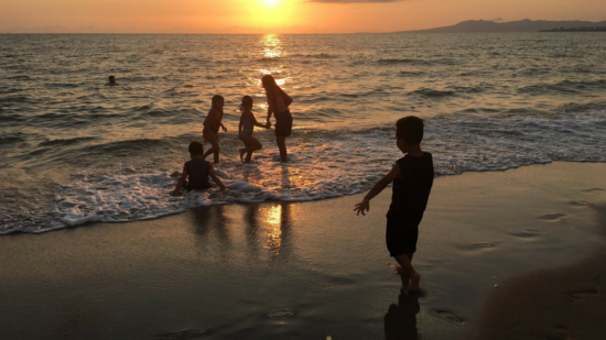 Children play under a beautiful sunset on the beach in Puerto Vallarta, Mexico.