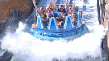 Guests are smiling and laughing excitedly while riding a white water rafting craft at a theme park/amusement park in Orlando, Florida.