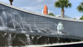John F. Kennedy (JFK) Quote with fountain in foreground and space shuttle atlantis in background