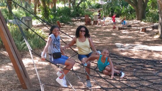 black mother and her two daughters pose smiling at the camera at the spider climb bok tower