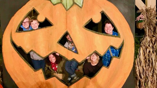 family posing behind pumpkin cutout at The Blaze in Croton NY