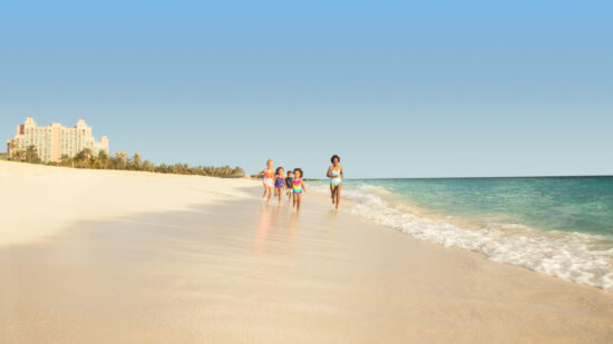 best atlantis hotel for your visit - mom and kids running on the beach at Atlantis Paradise Island.